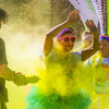 Someone being thrown yellow colour powder at her with a squeezing bottle while doing a colour run