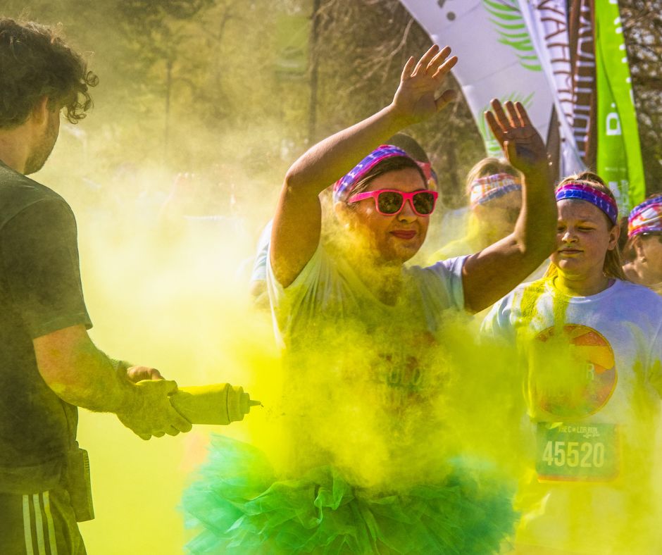 Someone being thrown yellow colour powder at her with a squeezing bottle while doing a colour run