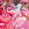 Someone being thrown pink colour powder at her with a squeezing bottle while doing a colour run