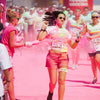Someone being thrown pink colour powder at her with a squeezing bottle while doing a colour run