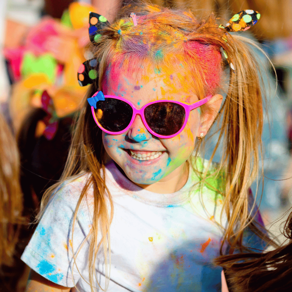 A girl wearing a white t-shirt with colour powders on it